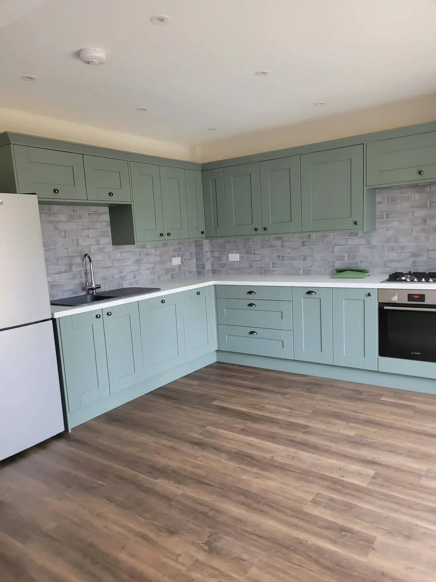 A kitchen with a white refrigerator freezer next to a stove top oven.