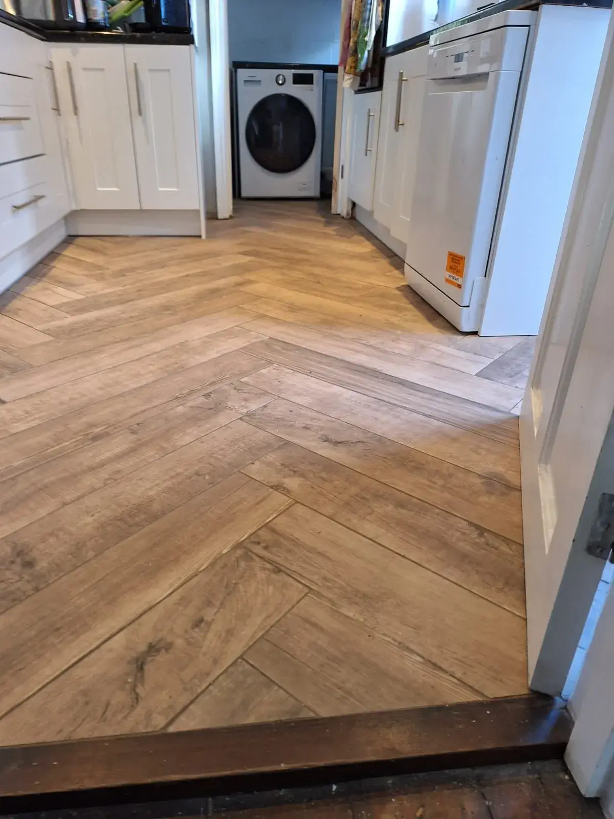 A kitchen with a wood floor and white cabinets.